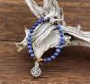 D'un bleu de cobalt doux et soutenu légèrement marbré, ce joli bracelet de perles de Sodalite est équilibré par quatre perles de pierre Oeil de tigre aux reflets d'or. Une perle-cylindre à prières et une médaille-talisman Arbre-de-Vie de métal argenté