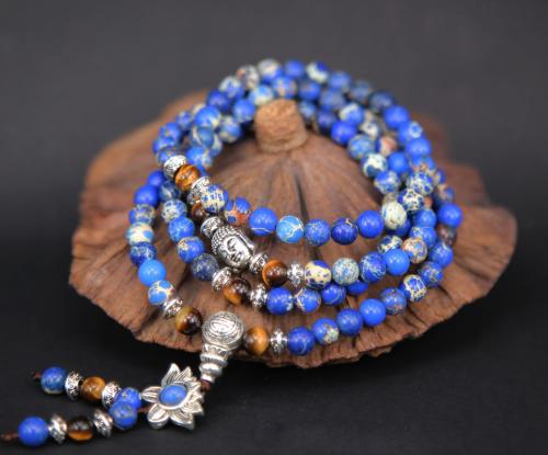 Mala de prières tibétain 108 perles de pierres Jaspe bleu et Oeil de tigre avec un portrait de Bouddha et une fleur de lotus symbolique de métal argenté, créé à la main par mes soins.​ Diamètre des perles: 6mm, longueur: 40cm