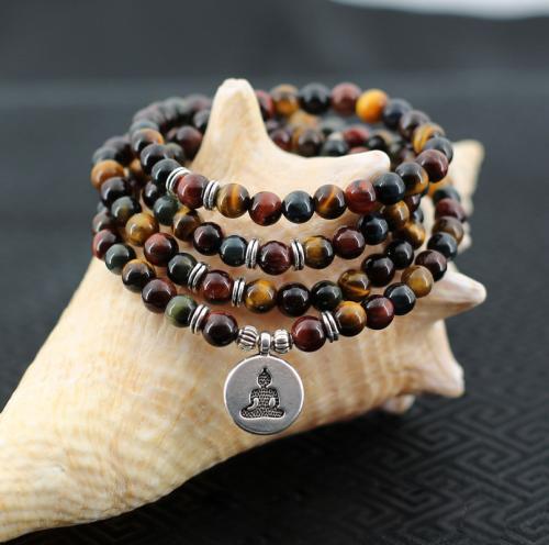 Chapelet Bouddhiste tibétain de protection confectionné à partir de 108 perles de pierres Oeil de tigre, Oeil de taureau, Oeil de faucon.​ Des accessoires symboliques fait que chaque modèle de mala peut revêtir une signification différente.
